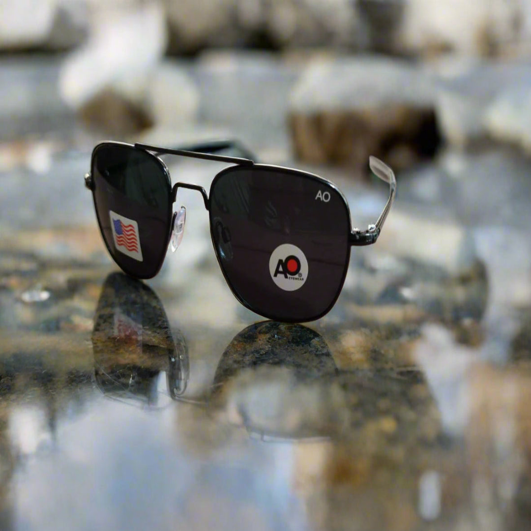 Black sunglasses with a logo on a reflective surface