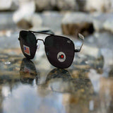 Black sunglasses with a logo on a reflective surface