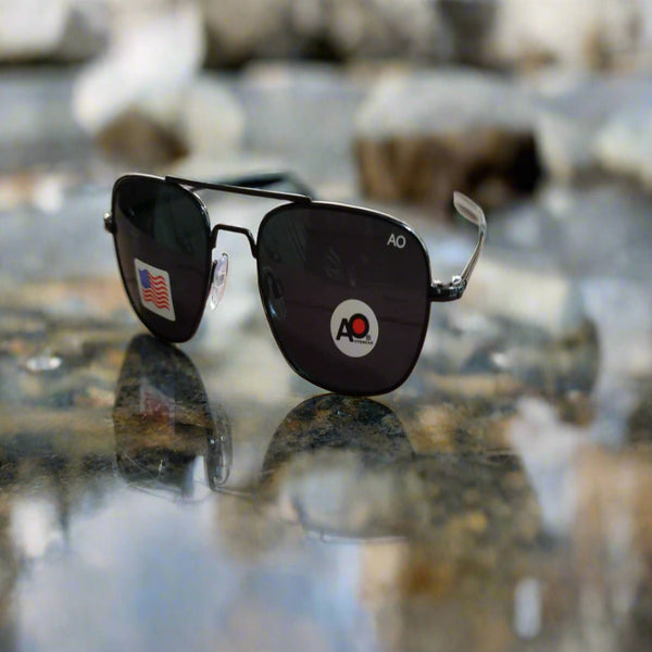 Black sunglasses with a logo on a reflective surface