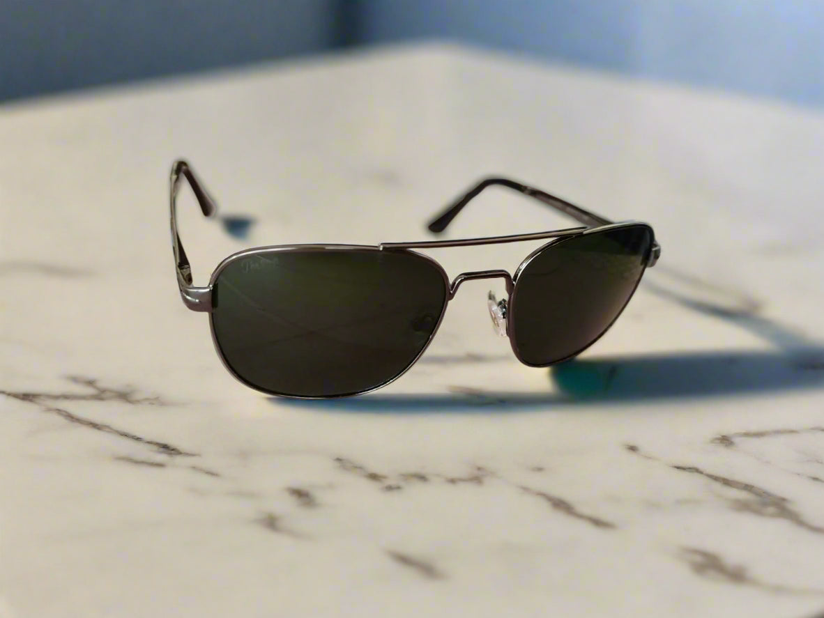 Aviator sunglasses on a pink surface with a blurred background