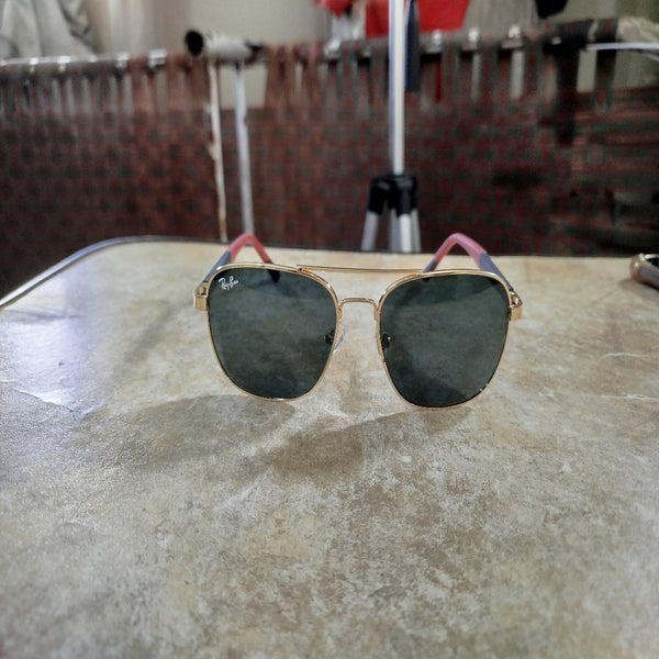 Sunglasses with gold frame and dark lenses on a textured surface
