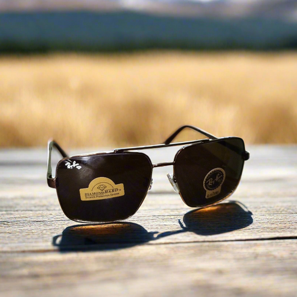 Sunglasses with a brand logo on a wooden surface with a blurred natural background