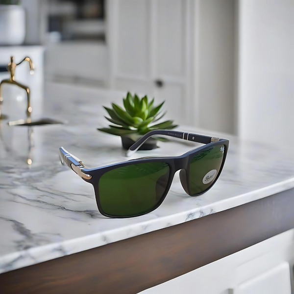 A pair of Persol Wayfarer sunglasses with a matte finish, displayed on a marble surface. The lenses are tinted green and the frame is black.