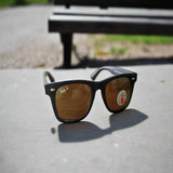 Ray-Ban sunglasses on a concrete surface with a blurred bench in the background