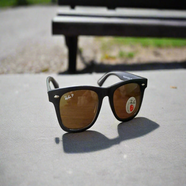 Ray-Ban sunglasses on a concrete surface with a blurred bench in the background