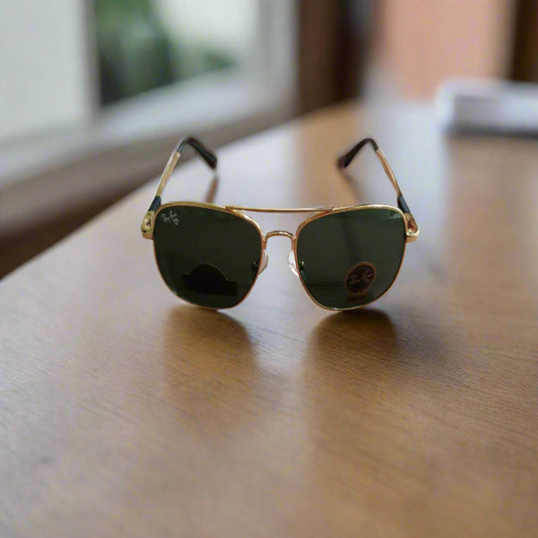 Gold-framed sunglasses with green lenses on a wooden surface