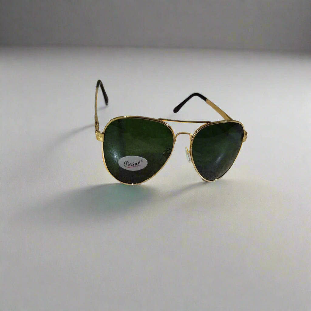 Aviator sunglasses with gold frame and green lenses on a marble surface