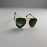Aviator sunglasses with gold frame and green lenses on a marble surface
