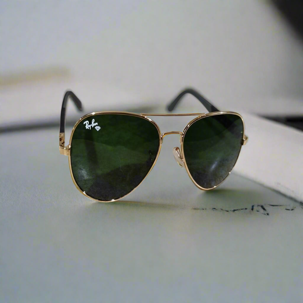 Gold-framed sunglasses with green lenses on a marble surface