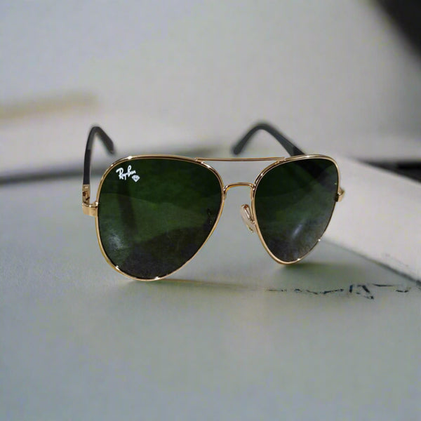 Gold-framed sunglasses with green lenses on a marble surface