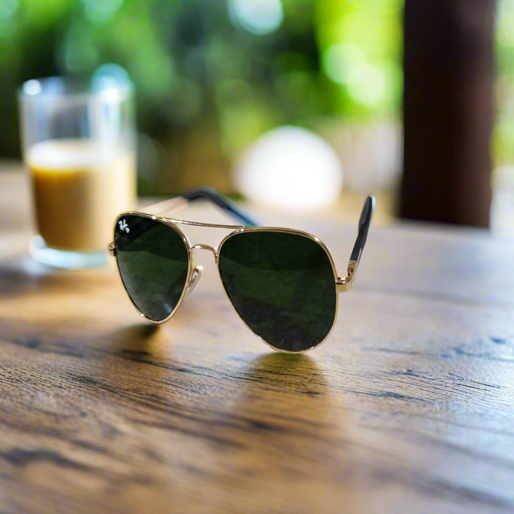 Aviator sunglasses with gold frame and dark lenses on a textured surface.