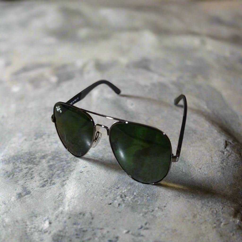 Aviator sunglasses with green lenses on a textured surface