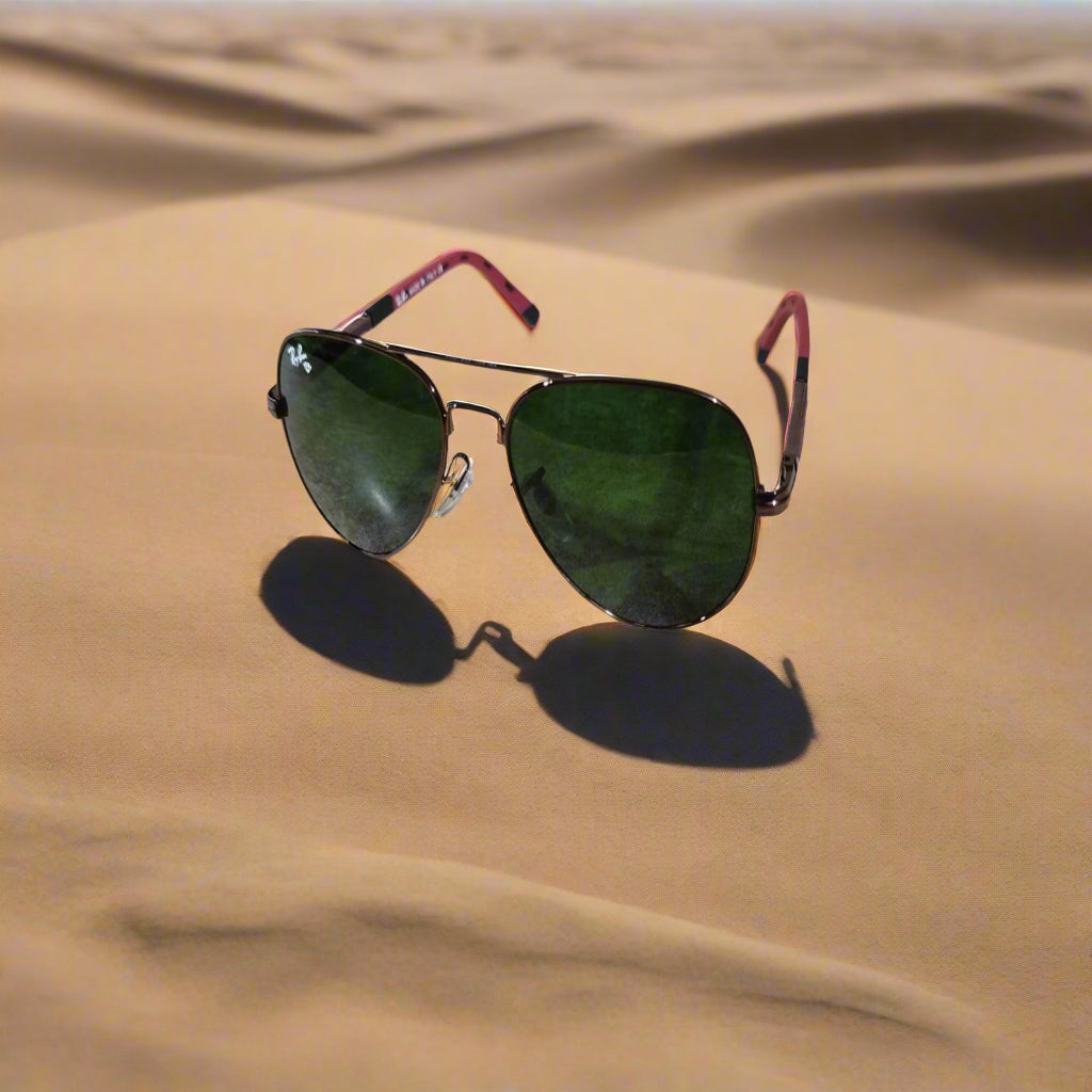 Sunglasses with green lenses and red frames on a textured surface