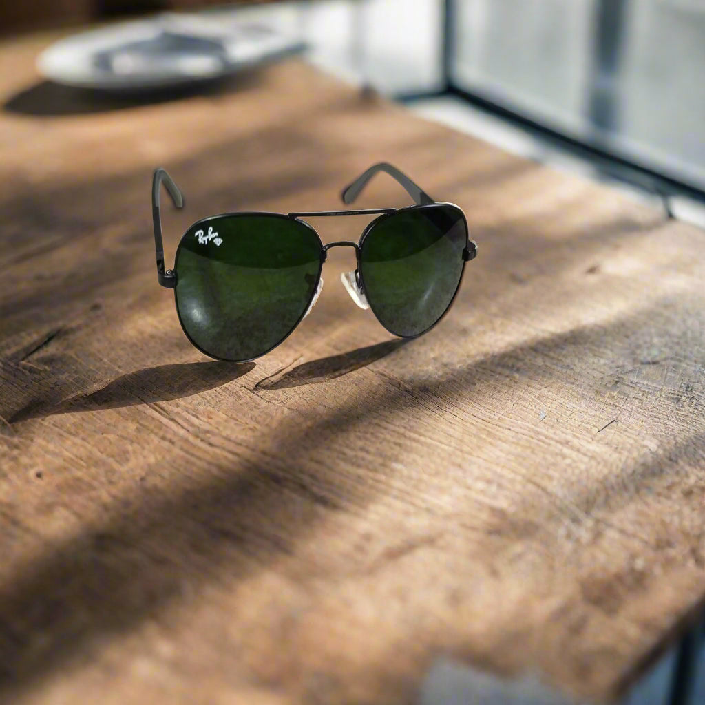 Aviator sunglasses with green lenses on a marble surface