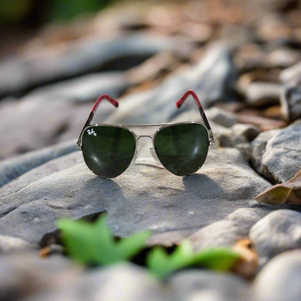 Sunglasses with green lenses and red arms on a textured surface