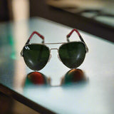 Aviator sunglasses with green lenses on a textured surface