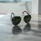 Aviator sunglasses with green lenses on a textured surface